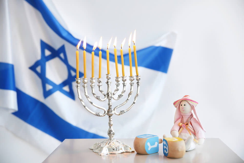 Menorah with lit candles in front of a Israeli flag