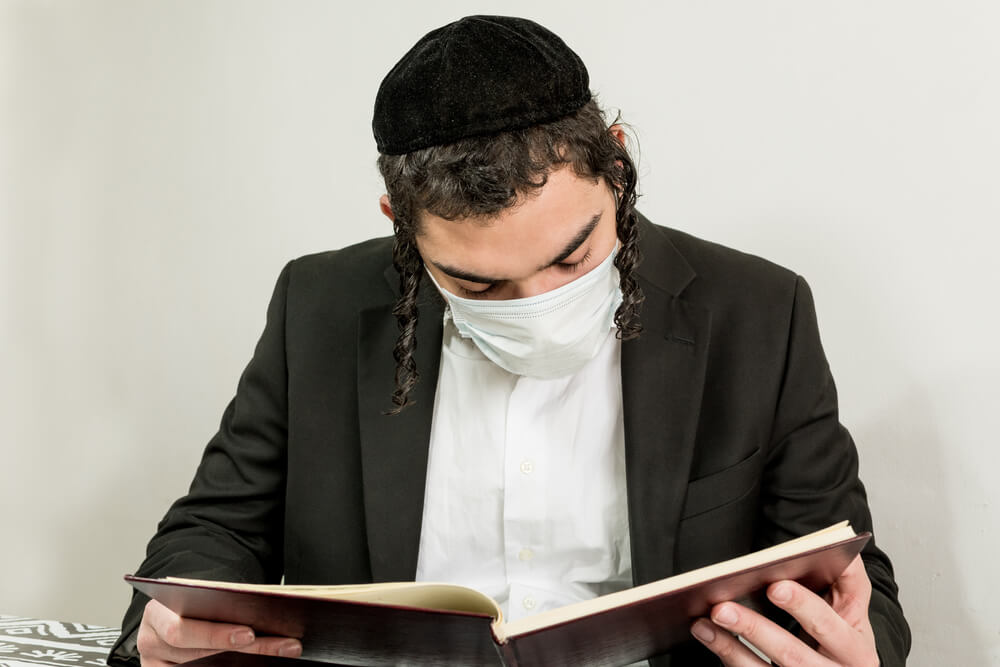 Young Orthodox Jew With Surgical Mask, Studying Religious Texts