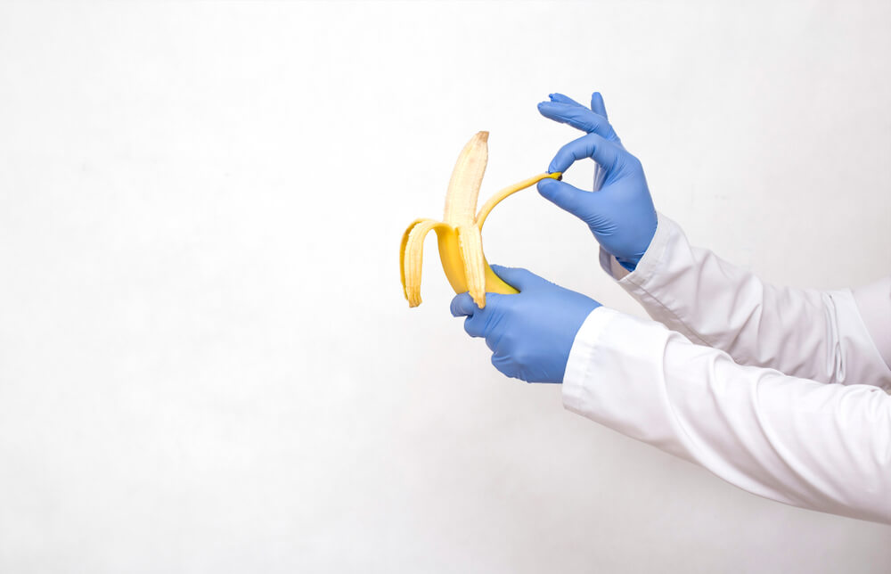 Doctor Holding a Banana in His Hands and Peels