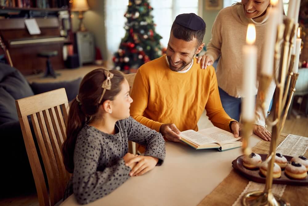 Happy Jewish Parents and Their Daughter Talking While Reading Tanakh During Hanukkah at Home