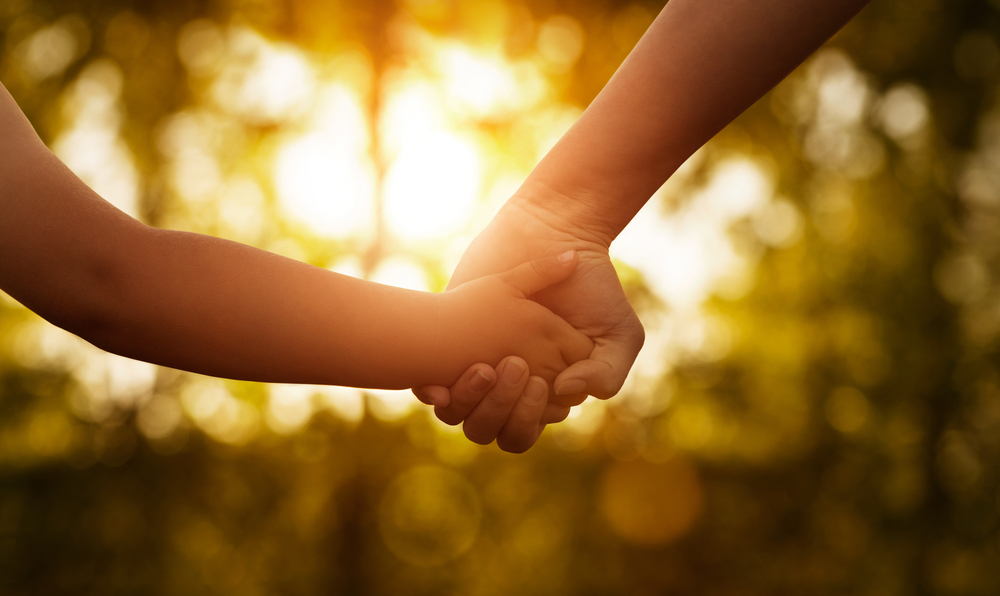 Close Up of Mother or Older Sister and a Child Hands at the Sunset With Copy Space