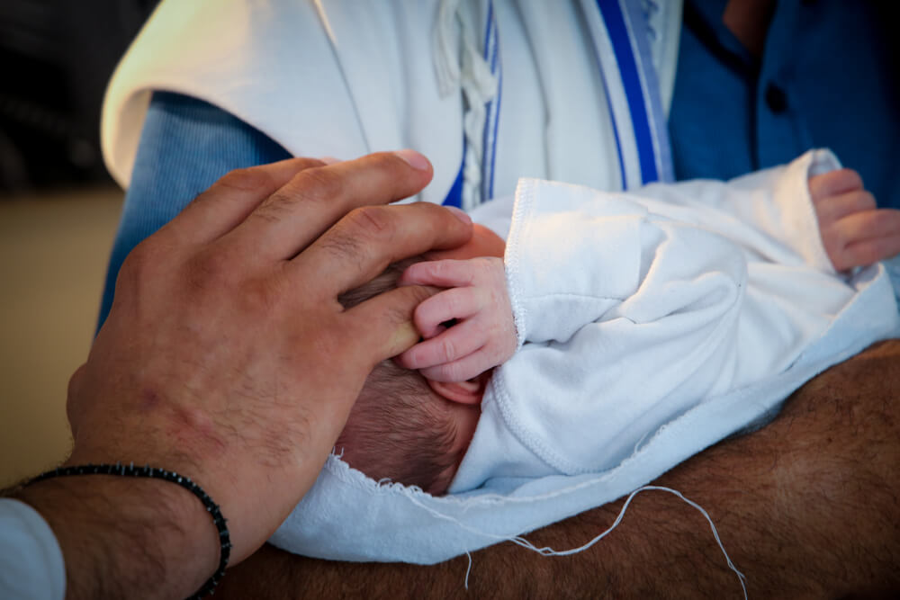 Father Holds a Baby’s Hand in a Circumcision Ceremony
